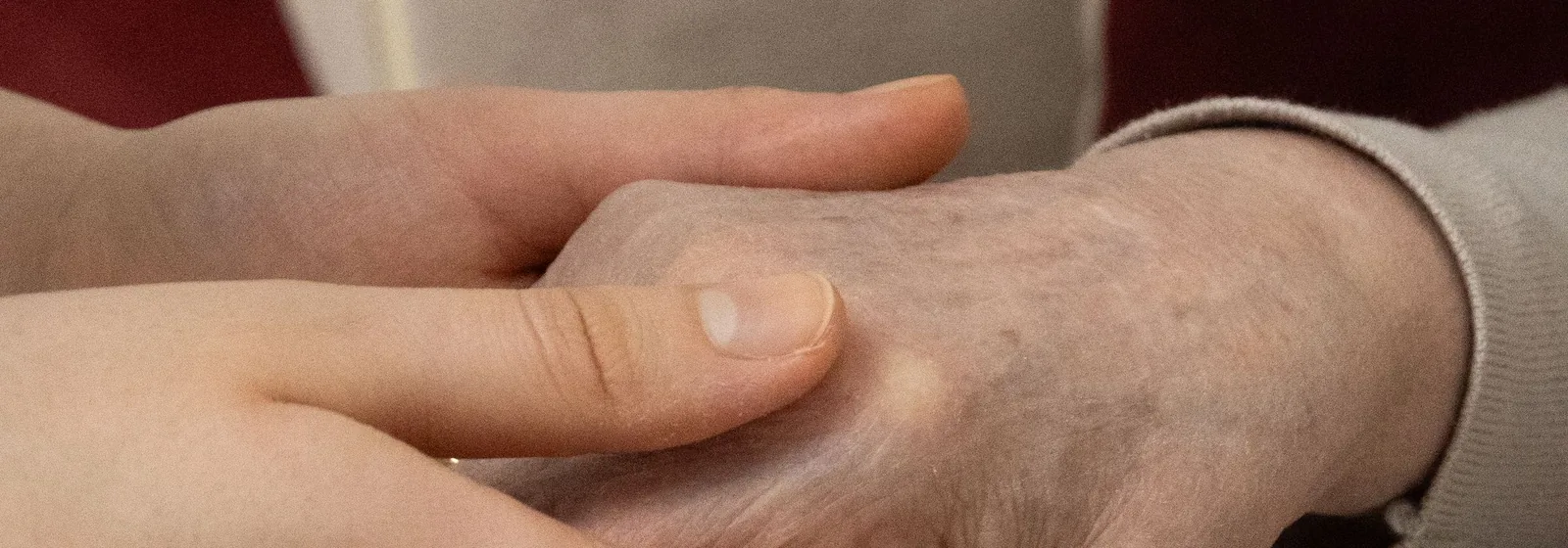 Cuidadora a segurar a mão de uma pessoa sénior